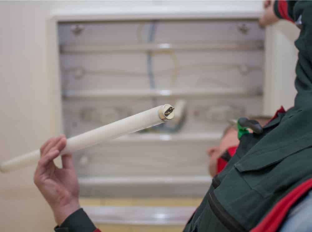 A residential electrician prepares to replace a fluorescent light tube.